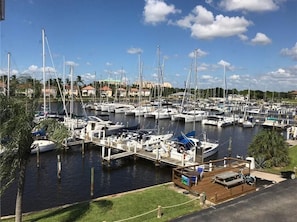 Un puerto deportivo con varias embarcaciones amarradas, un muelle de madera y un cielo despejado.