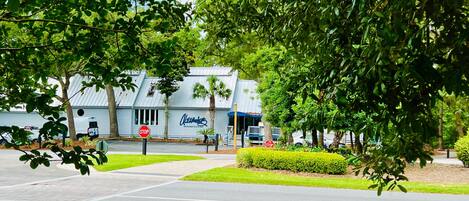 A restaurant with a sign reading "Alexander's Restaurant & Bar" in a landscaped area with trees and a sidewalk.