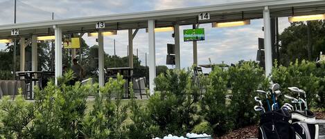 A golf course with numbered lanes, green baskets, and a golf bag.