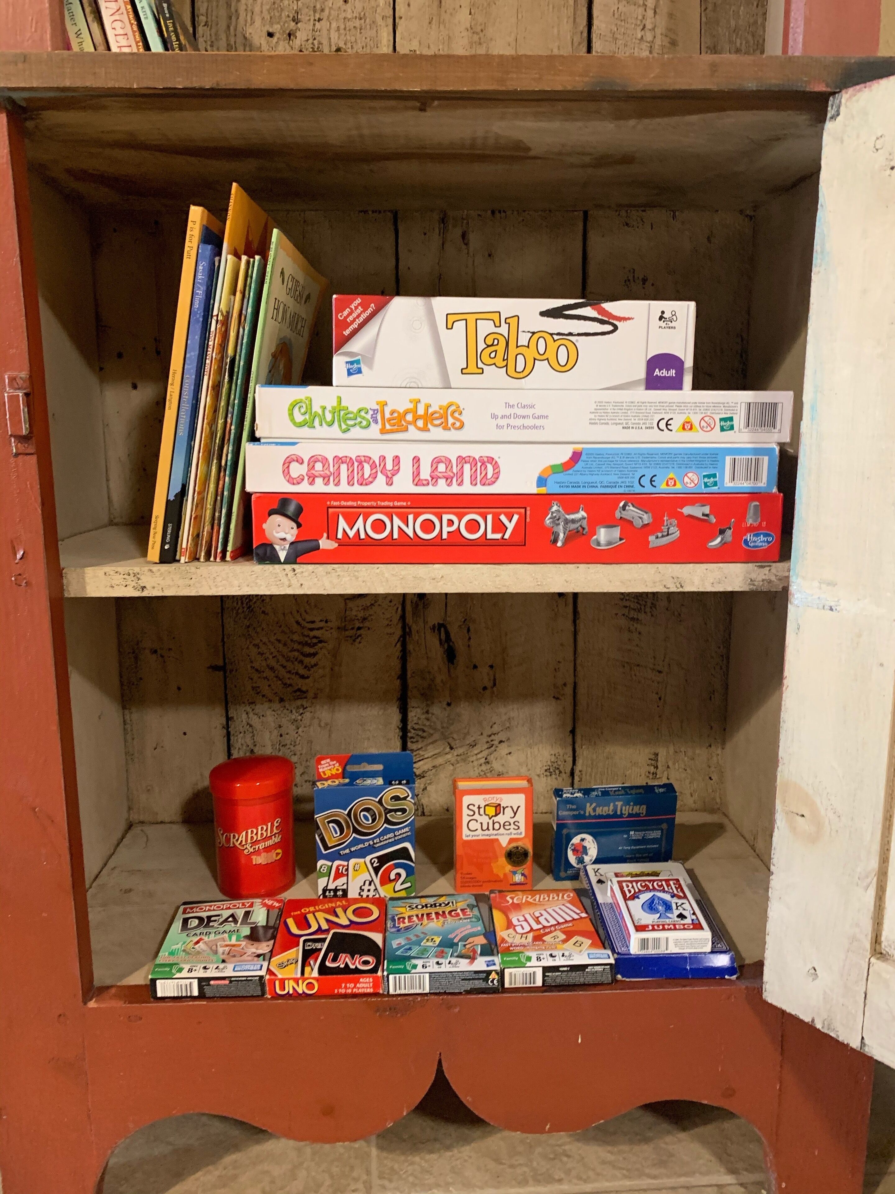 Una estantería de madera con varios juegos de mesa y libros.