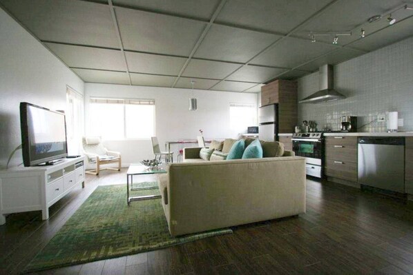 A modern living room with a sofa, television, and a dining area.