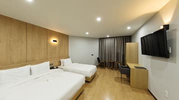 Habitación de hotel con dos camas, un escritorio, una silla, un televisor y una cortina.