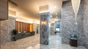 A spacious lobby with marble flooring, a reception desk, and a glass display case. - Notte La Mia (Busan)
