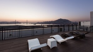 A rooftop terrace with lounge chairs and a view of a river and cityscape. - Notte La Mia (Busan)