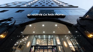 The entrance of the Nuit de la Mia Hotel with a modern glass facade and illuminated signage. - Notte La Mia (Busan)