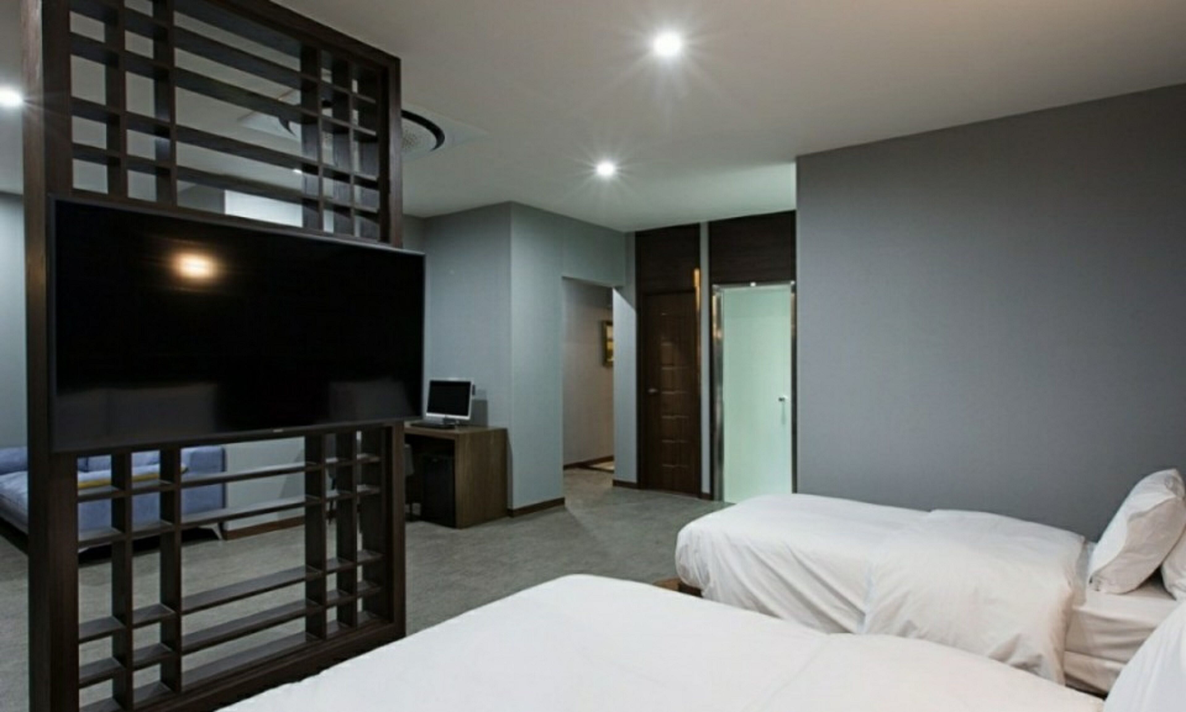 A hotel room with two beds, a TV, a desk with a computer, and a wardrobe.