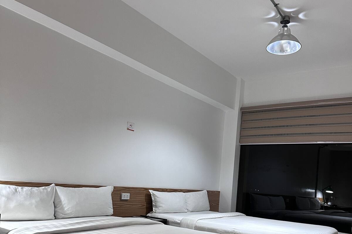 A modern hotel room with two beds, a wooden headboard, a flat-screen TV, and a ceiling fan.