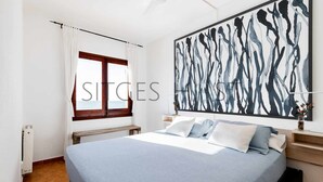 Een slaapkamer met een bed, een raam met gordijnen, een plafondventilator en een groot abstract schilderij aan de muur.