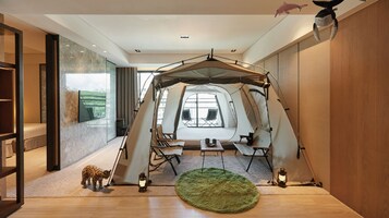 Habitación con toldo y vistas a la ciudad, una mesita con sillas y una alfombra verde.