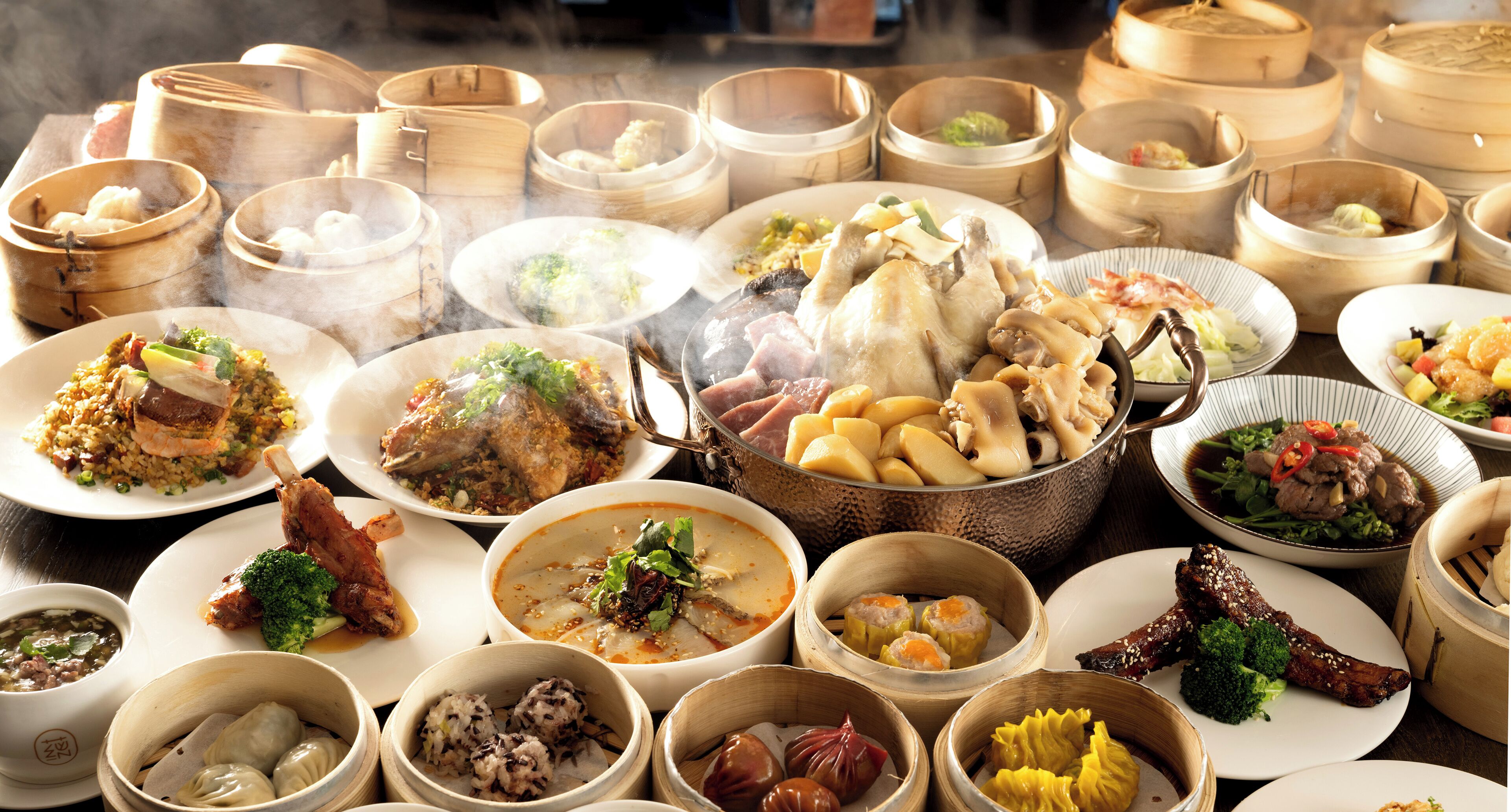 A variety of dishes in bamboo steamers and on plates, suggesting a diverse meal selection.