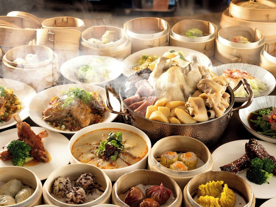 A variety of dishes in bamboo steamers and on plates, suggesting a diverse meal selection.