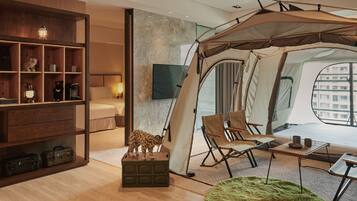A tented room with a bed, chairs, a table, and a bookshelf.