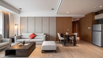 Quarto de hotel moderno com área de estar, espaço para refeições e cozinha compacta.