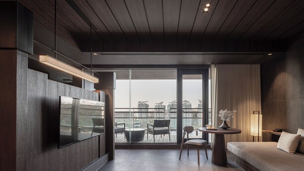 Une chambre d’hôtel moderne dotée d’une grande télévision, d’un canapé, d’une petite table et d’un balcon offrant une vue sur la ville.