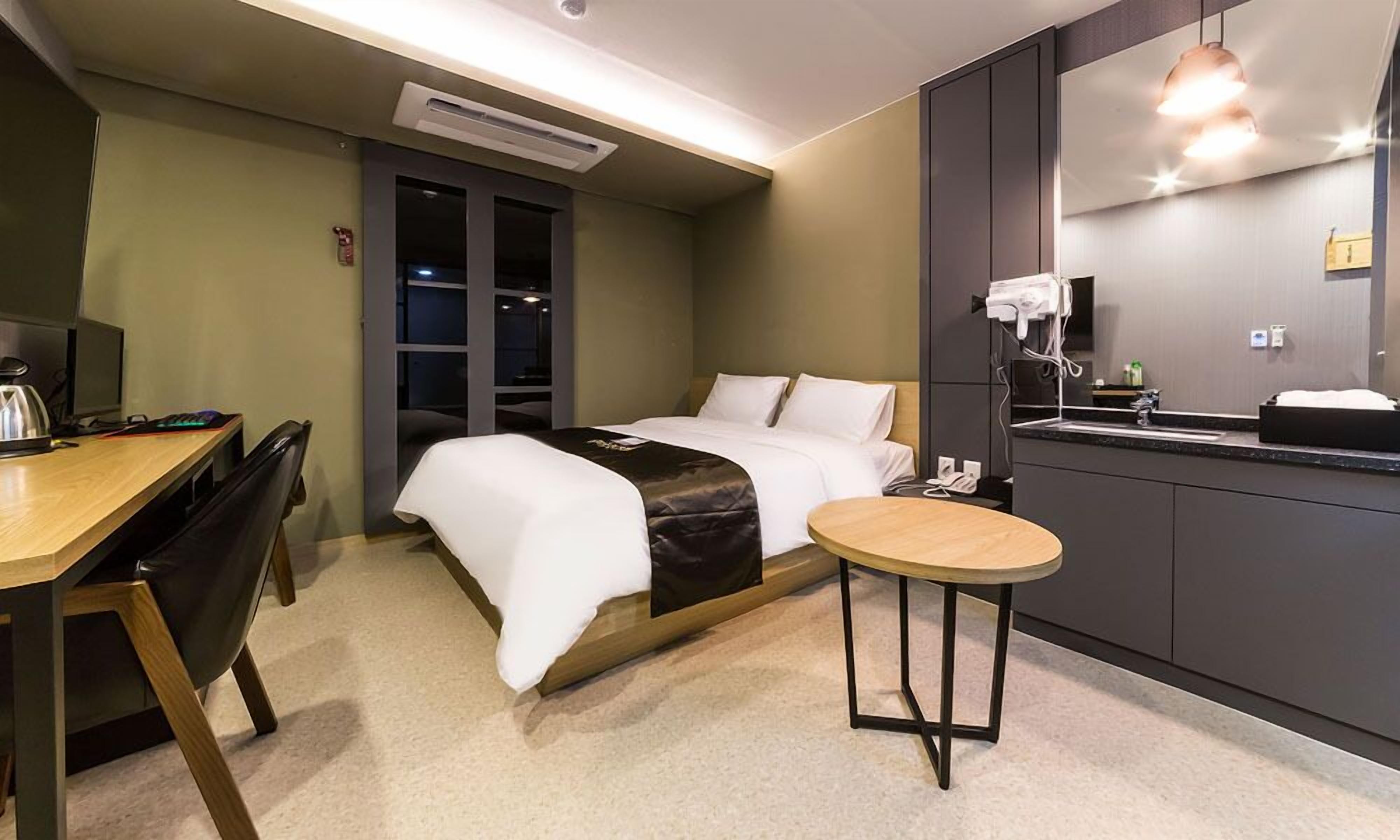 A hotel room with a bed, desk, chair, and a small round table.