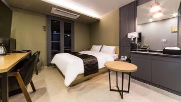 A hotel room with a bed, desk, chair, and a small round table.