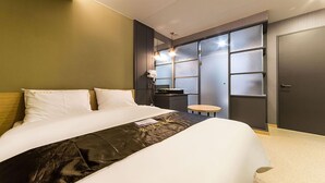 Ein modernes Hotelzimmer mit einem großen Bett, einem kleinen runden Tisch und einem Schrank mit Milchglas-Türen.