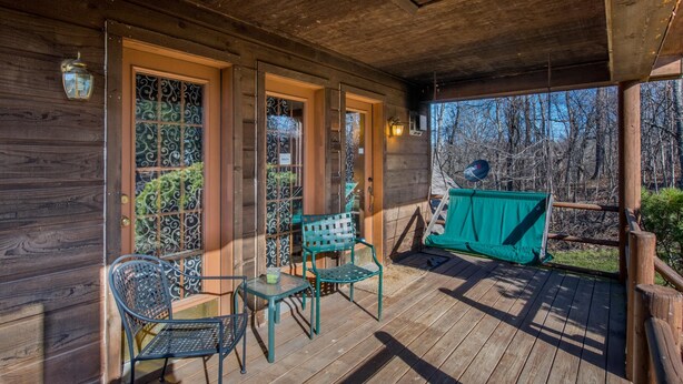 Una terraza de madera con zona de estar cubierta, que incluye dos sillas y una mesa.
