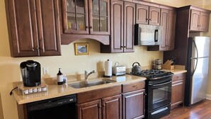 Una cocina con armarios de madera, lavavajillas, estufa y refrigerador.