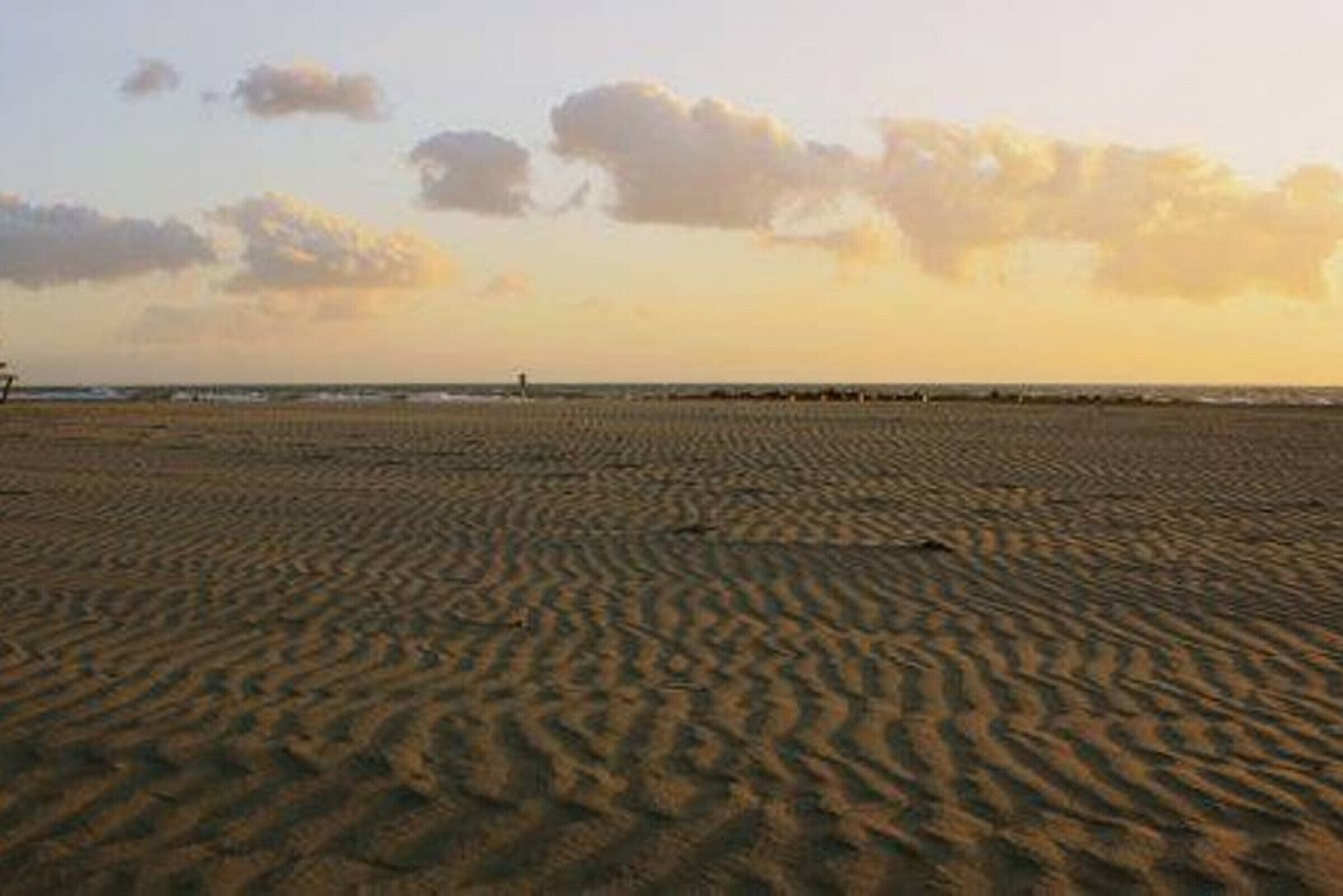 A sandy beach with a clear sky and a few clouds.