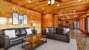 A spacious living room with two leather sofas, a wooden coffee table, and a ceiling fan. - Lookout Lodge ~ Indoor Pool, Hot Tub & Mountain Views! (Sevierville)