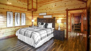 A wooden cabin-style bedroom with a large bed, wooden walls, and a wooden ceiling. - Lookout Lodge ~ Indoor Pool, Hot Tub & Mountain Views! (Sevierville)