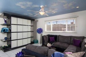 Relax in this stylish living room with a large sofa, ceiling fan, and floor-to-ceiling window.