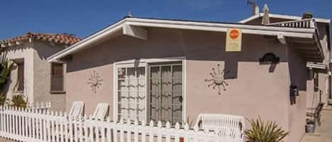 A building with a white picket fence, a clock, and a sign on the wall.