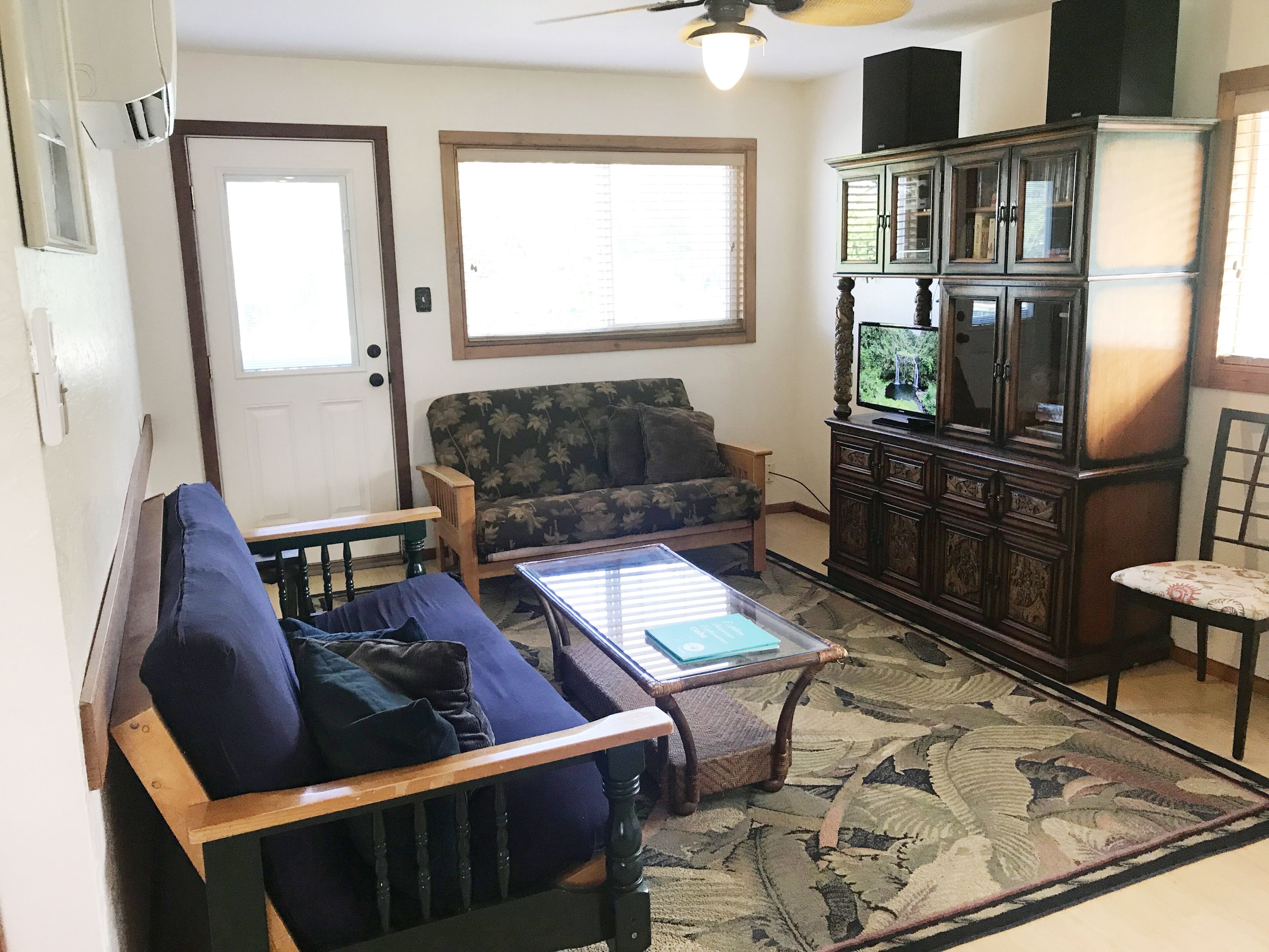 A living room with a sofa, a coffee table, a television, and a cabinet.