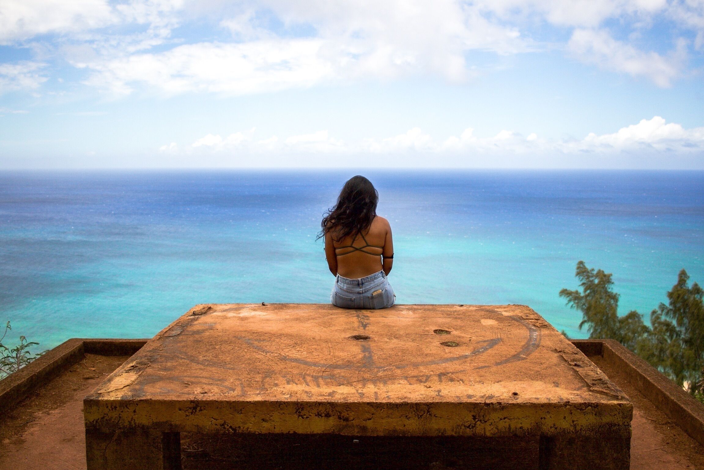 A person sitting on a wooden platform overlooking a body of water.