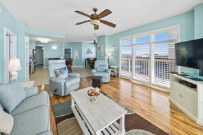 Relax in a spacious living area with a sofa, armchairs, and a TV on a cabinet.