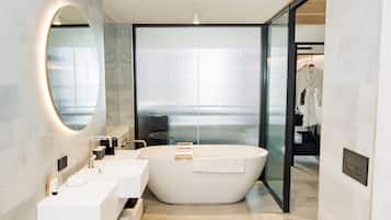 A modern bathroom with a freestanding bathtub, two sinks, and a large mirror.