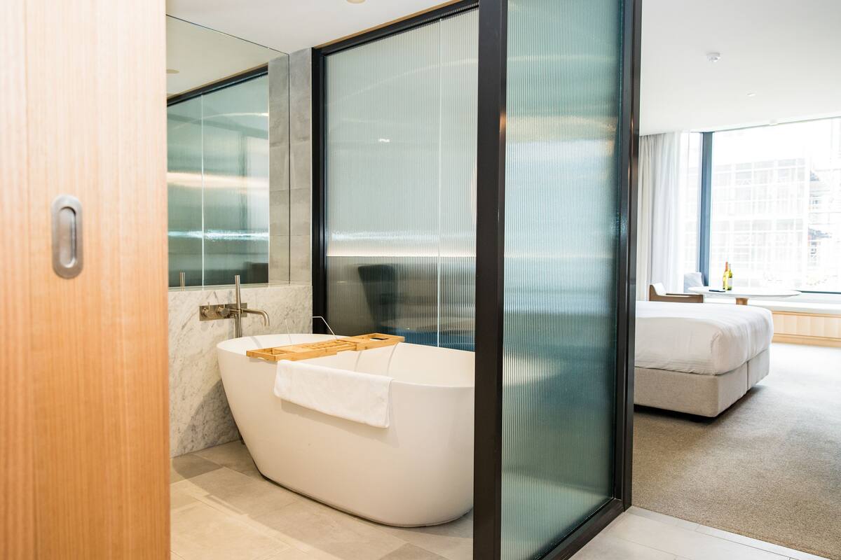 Une salle de bain moderne avec une baignoire sur pieds, un grand miroir et une cloison en verre.