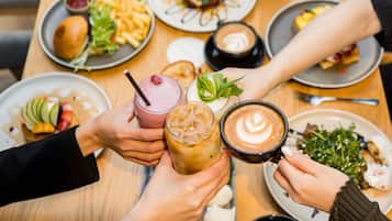 Un groupe de personnes est assis à une table, avec des boissons et de la nourriture.