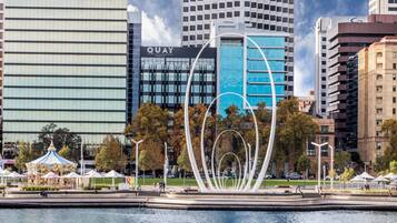 Una plaza urbana moderna con un elemento de agua, un carrusel y edificios contemporáneos al fondo.
