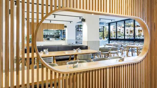 A modern restaurant with wooden slats, a central seating area, and a view of the city through large windows. - Quay Perth (Perth)