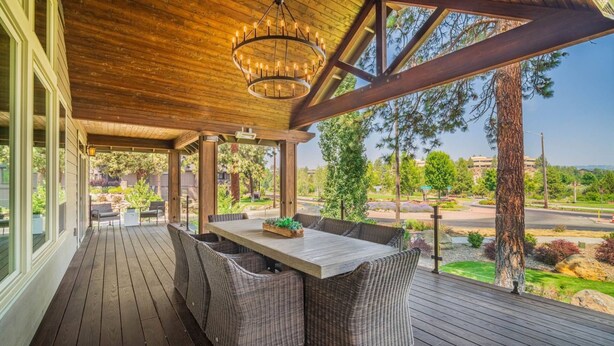 Eine überdachte Terrasse im Freien mit Holzdeck, Korbmöbeln und einem zentralen Tisch.
