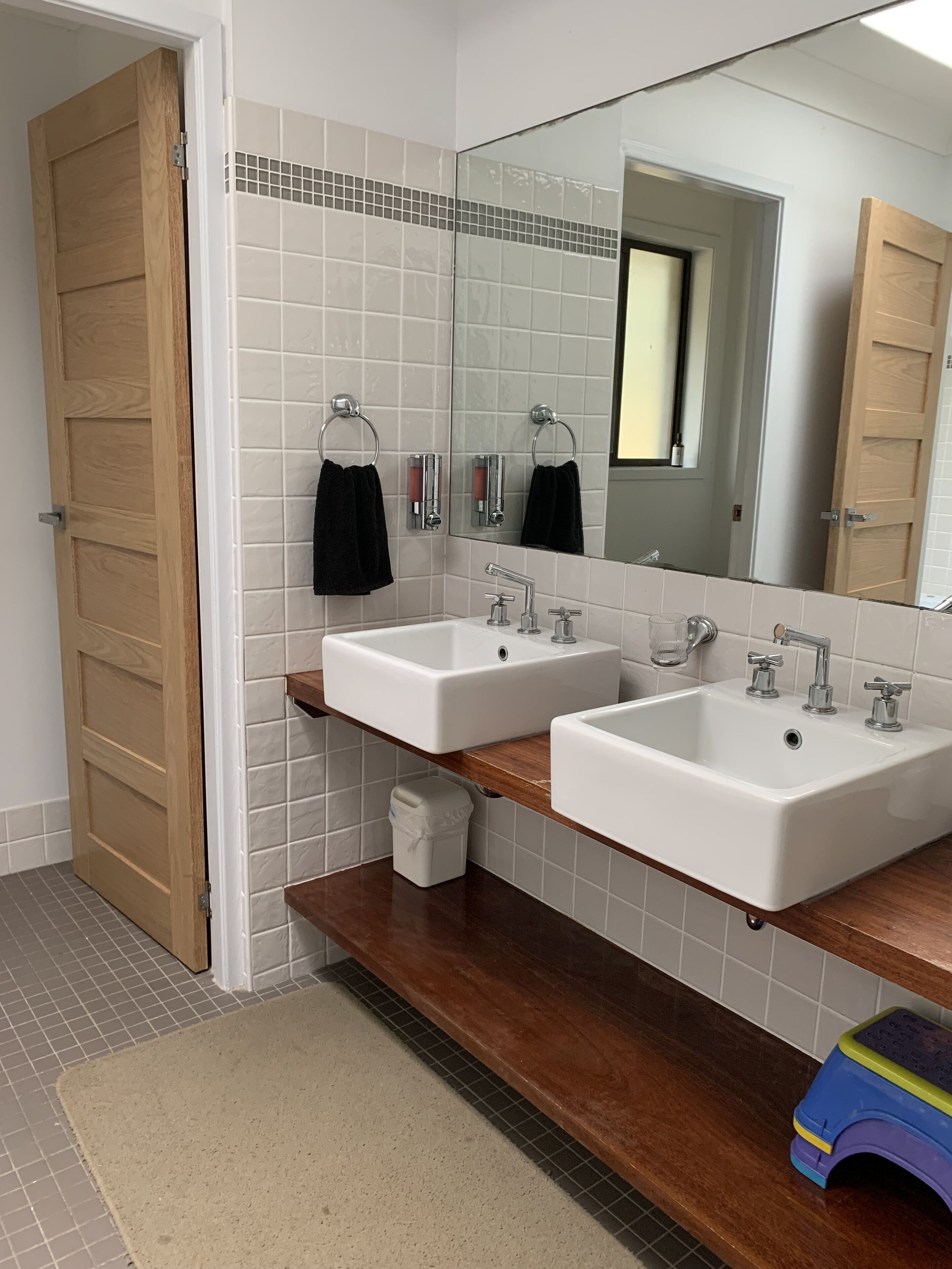 Un baño con dos lavamanos, un espejo y una puerta de madera.
