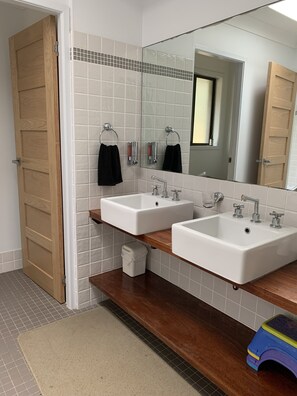 A bathroom with two sinks, a mirror, and a wooden door. - Family Friendly Beach House - 2min walk to Beach, Bushwalks & Open Fireplace (Vincentia)