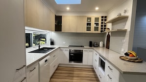 A modern kitchen with white cabinetry, a skylight, and a wooden floor.