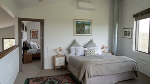 Une chambre à coucher avec un lit, des tables de chevet, une commode, un tapis et des œuvres d’art accrochées aux murs.