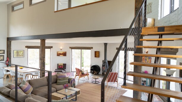 Un amplio salón con techo alto, una escalera de madera y una chimenea.
