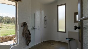 Une salle de bain avec une douche, une serviette suspendue, une fenêtre et une vue sur l’extérieur.