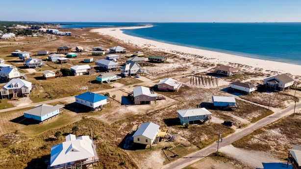 Vista aérea de una zona residencial costera con casas y una playa.