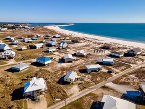 An aerial view of a coastal residential area with houses and a beach.
