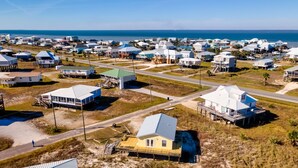 Vista aérea de una zona residencial costera con casas, caminos y una playa.