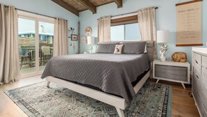 A bedroom with a bed, bedside tables, a clock, and a view of the outside. - Sea Dog- Pool, Crows Nest, Great View! 3 Bedrm,/3 Bath, Pet Friendly, Sleep 11 (Dauphin Island)