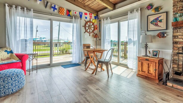 A spacious room with a wooden ceiling, a dining area with a table and chairs, a red sofa, and a wooden cabinet with a picture frame. - Sea Dog- Pool, Crows Nest, Great View! 3 Bedrm,/3 Bath, Pet Friendly, Sleep 11 (Dauphin Island)