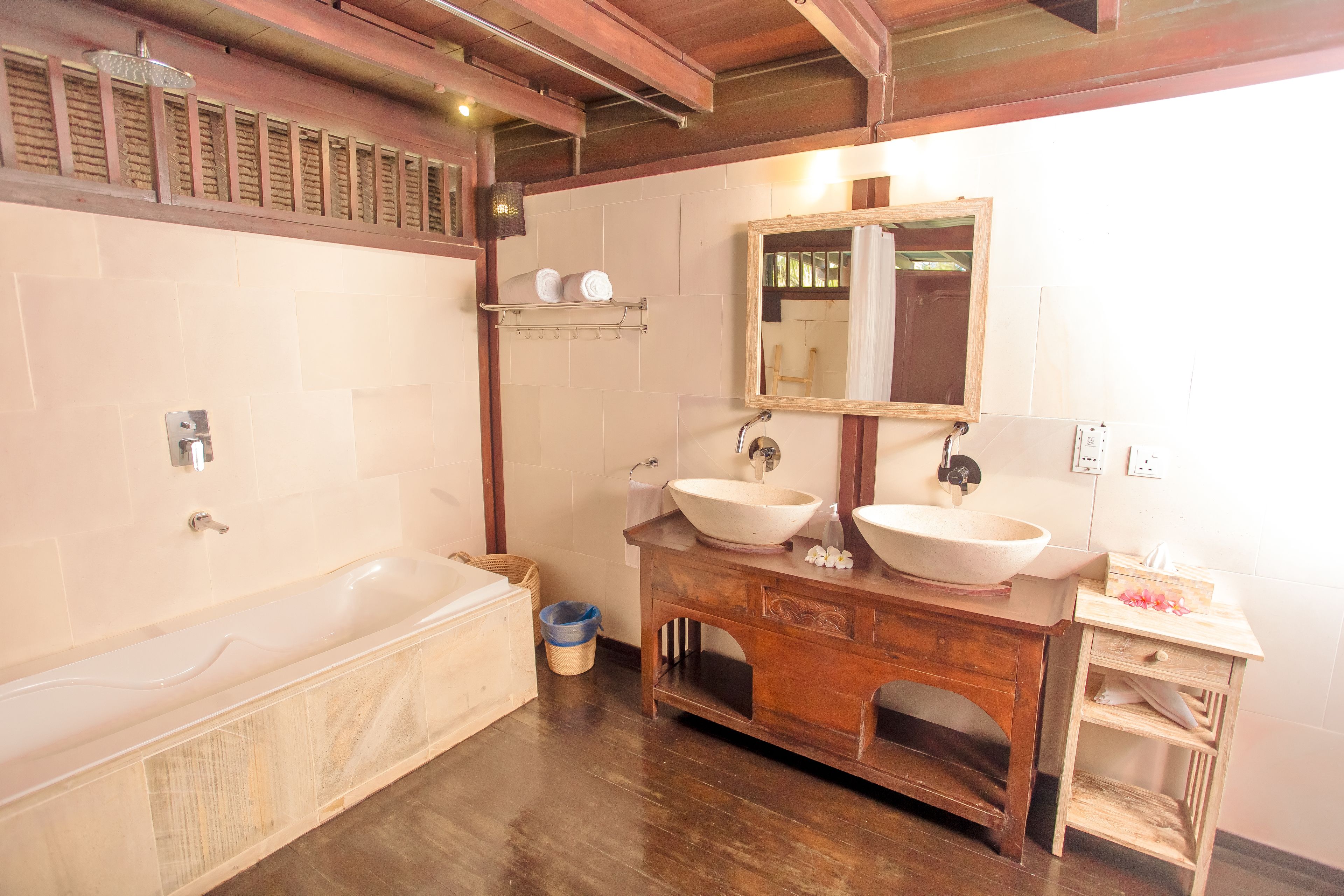 A bathroom with a bathtub, two sinks, a wooden vanity, and a mirror.