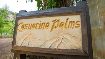 Uma placa de madeira com o texto 'Casuarina Palms' e um desenho de folha.